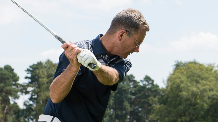 a-golfer-turning-through-his-swing-wearing-a-white-golf-glove