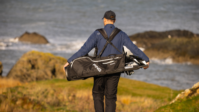 a-golfer-wearing-a-waterproof-jacket-and-trousers-standing-on-a-links-course