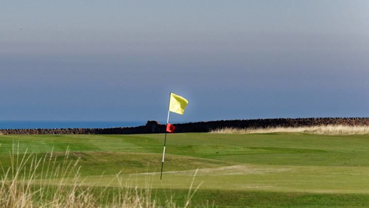 a-flag-on-a-green-being-bent-by-strong-wind