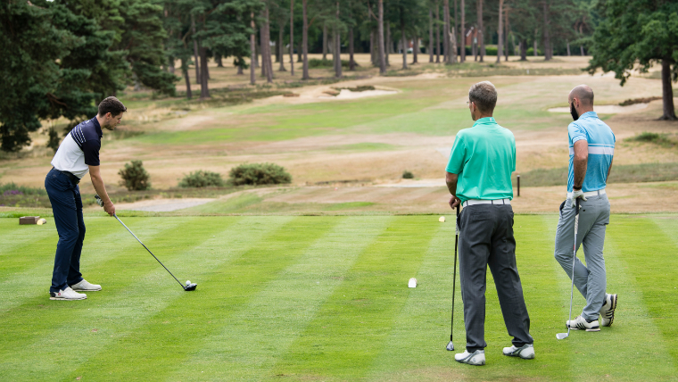 a-golfer-teeing-off-with-playing-partners-watching