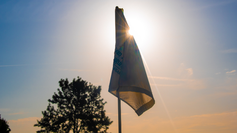 the-sun-shining-behind-a-golf-flag