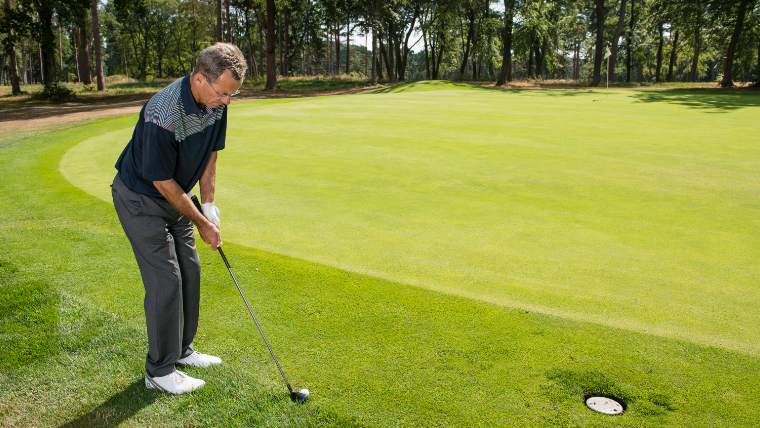 a-golfer-using-a-hybrid-on-the-edge-of-a-green