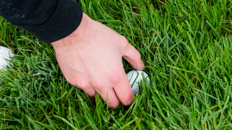 a-golfer-reaching-for-a-ball-in-thick-rough