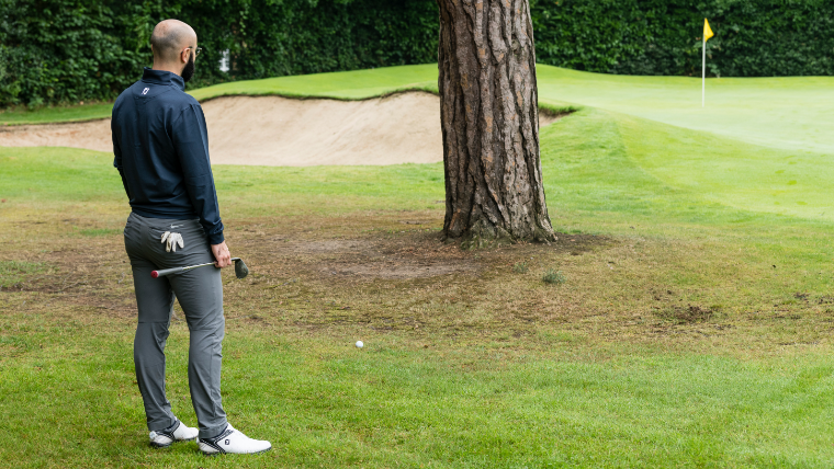a-golfer-standing-behind-a-tree