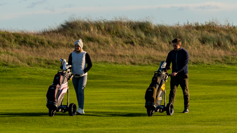 golfers-pushing-electric-trolleys